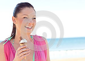 Joyful woman in bikini eating ice cream on beach