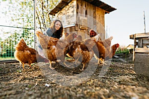 Joyful woman in chicken coop enjoying farm life by feeding chickens