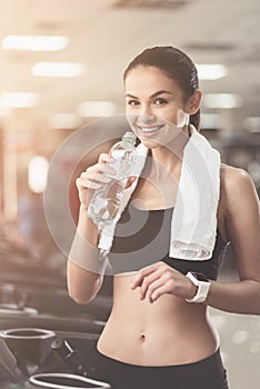 Joyful woman drinking water after sport exercises