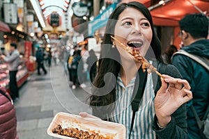 Joyful woman eating tasty yakitori