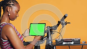 Joyful woman following tutorial videos on mockup tablet, learning to mend bike