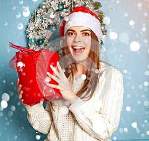 Joyful woman with gift on blue background bokeh snowflakes