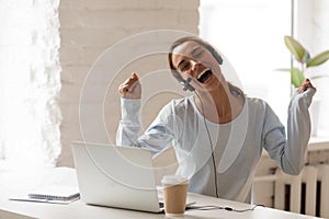 Joyful woman in headphones with microphone using laptop, sing an