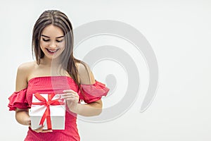 Joyful woman holding a gift box and smiling over a white background.