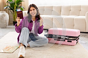 Joyful woman holding passport with suitcase closed photo