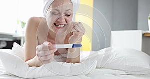 Joyful woman holding positive pregnancy test