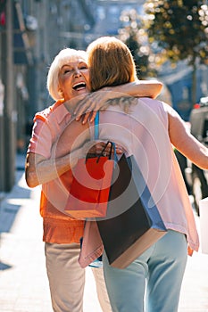 Joyful woman hugging daughter and smiling stock photo