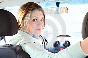 Joyful woman inside of car looking back