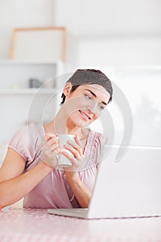 Joyful woman with laptop and a cup