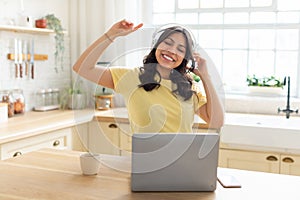 Joyful woman listening to music on laptop