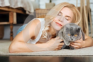 Joyful woman lying on the floor with her cat