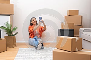 joyful woman moving day in new home, surrounded by carton boxes, video call with friends