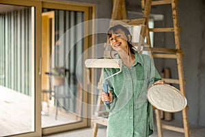 Joyful woman paints walls at home