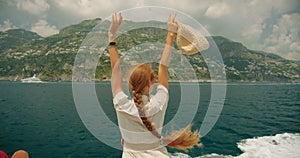Joyful woman rushing on boat with wind, hair fluttering freely. Letting go and living in the moment amidst the beauty of