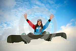 Joyful woman snowboarder sitting on top of mountain on blue sky