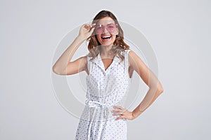 Joyful woman in sunglasses posing on background