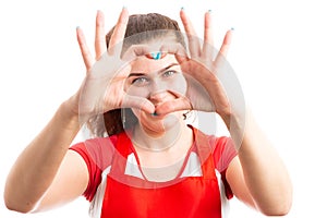 Joyful woman supermarket employee making heart sign with hands