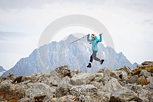 Joyful happy traveler woman jumping over stones on the background of a high mountain