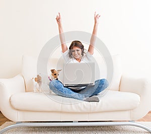 Joyful woman using laptop on the sofa