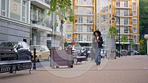 Joyful woman walking texting friends online. Modern residential area district.