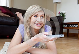 Joyful woman watching TV lying on the floor