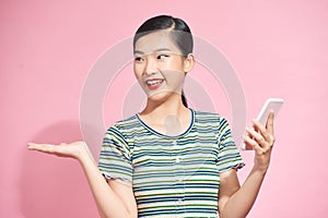 Joyful woman waves at camera of smart phone, makes video call, over pink background. Hello, friend