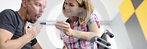 Joyful woman in wheelchair shows surprised man pregnancy test