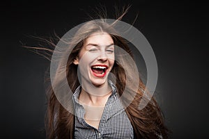 Joyful woman winking with flying hair and wind in her face.