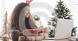 Joyful woman wrapping Christmas gift at office