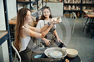 Joyful women potters working with clay and pottery wheel