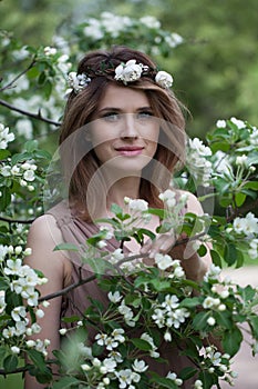 Joyful young adult woman female model with clean fresh skin, make-up and brown hair in blossom garden on green leaves background