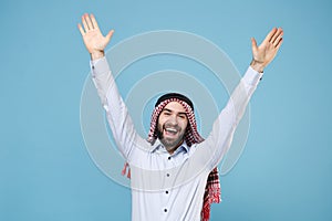 Joyful young bearded arabian muslim man in keffiyeh kafiya ring igal agal casual clothes isolated on pastel blue