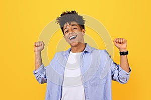 Joyful young black man celebrating with raised fists