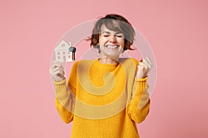 Joyful young brunette woman girl in yellow sweater posing isolated on pastel pink background in studio. People lifestyle