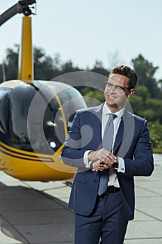 Joyful young businessman waiting for a helicopter pilot