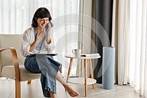 Joyful young caucasian woman talking on modern smartphone in her spare time at home.