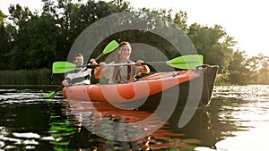 Joyful young couple having fun while kayaking in a river surrounded by the beautiful nature on a summer day