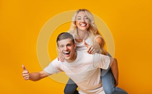 Joyful young couple having fun together and showing thumbs up