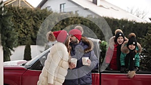 Joyful young family, kids in winter clothes kiss near car with Christmas tree spending xmas wintertime weekend together