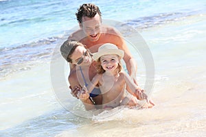 Joyful young family playing around on the beach