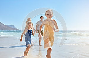 Joyful young family with two children running on the beach and enjoying a fun summer vacation. Two energetic little