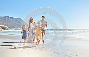 Joyful young family with two children running on the beach and enjoying summer vacation. Two energetic little girls