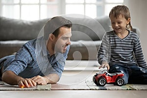 Joyful young father playing car toys with son.