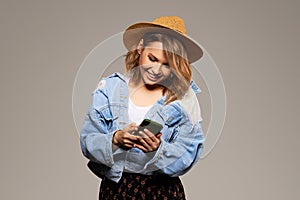 Joyful young girl in a hat with a mobile phone in her hands. The concept of 5G cellular and unlimited