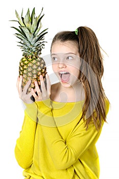 Joyful young girl holding a large pineapple.