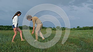 Joyful young guy with a girl in love walk and have fun on green grass on nature in hmarnaya weather