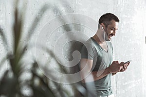 Joyful young guy is listening to music using his phone