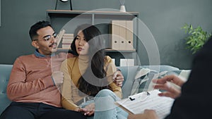 Joyful young husband and wife talking during counseling session with professional therapist