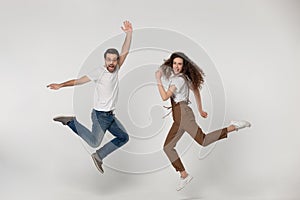 Joyful young man and happy millennial girl jumping high.