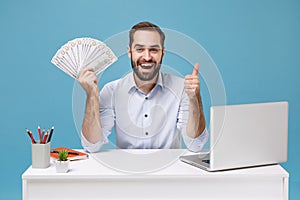 Joyful young man in shirt work at desk with pc laptop isolated on blue background. Achievement business career concept